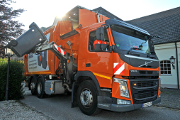 Side loader - Picture 2 The ESB empties most refuse containers with a side-loader vehicle. The gripper arm grasps a residual waste bin and empties it at the top of the loading opening. The driver in the picture is Maik van Drünen.