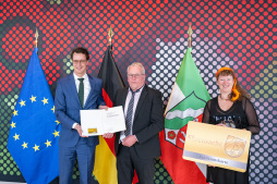  Ministerpräsident Hendrik Wüst (links) überreicht gemeinsam mit Staatssekretärin Andrea Milz die Jubiläums-Ehrenamtskarte an den Bocholter Leo Engenhorst. 