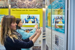 Wanderausstellung des Deutschen Bundestages Besucherinnen und Besucher informieren sich in der Wanderausstellung über den Deutschen Bundestag. Neben Informationen auf den Ausstellungstafeln und Bildschirmen erhalten Besucher über QR-Codes weiterführende Infos auf ihr Smartphone.