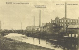  Textilindustrie in Bocholt auf einer Historischen Postkarte von 1925 mit der Brücke für den Zug nach Borken. Am Ufer der Bocholter Aa befinden sich die Aktiengesellschaft für Baumwollindustrie (heute LernWerk) und im Hintergrund die Spinnerei und Weberei Herding (heute LWL-TextilWerk) 