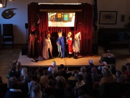 Puppenspiel Flocke und der Weihnachtszauber - Kinder Vier Kinder stehen als Prinzessin, König, Fee und Zauberer verkleidet vor der Märchenbühne.
