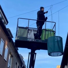 Stadtmarketing-Mitarbeiter Tim Becker beim Aufhängen der Lampenschirme.