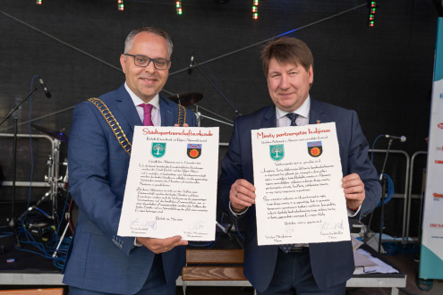 Bürgermeister Thomas Kerkhoff (links) und Bürgermeister Vitalijus Mitrofanovas (rechts) präsentieren die Städtepartnerschaftsurkunden zwischen der Stadt Bocholt und dem Rajon Akmene nach ihrer Unterzeichnung. 