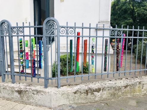 Der Zaun vom Kusthaus ist mit bunt bemalten Steelen der Kinder dekoriert.