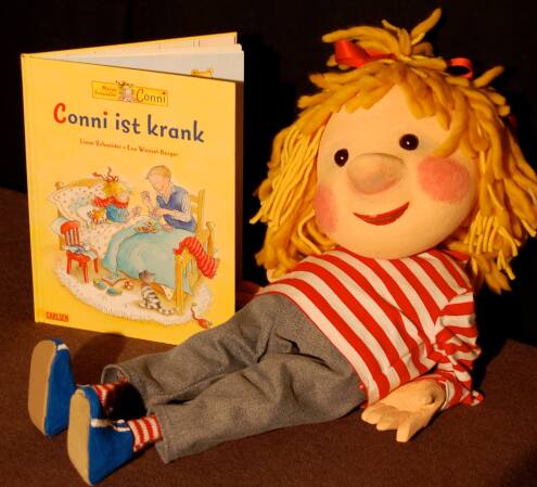 Conni liegend neben einem Buch
